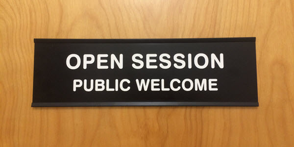 Picture of a door with a sign that says "Open Session. Public Welcome"
